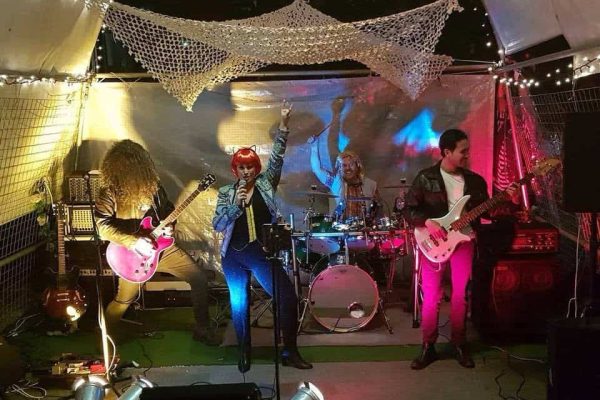 Live band performing on stage with colorful lighting and musical instruments.